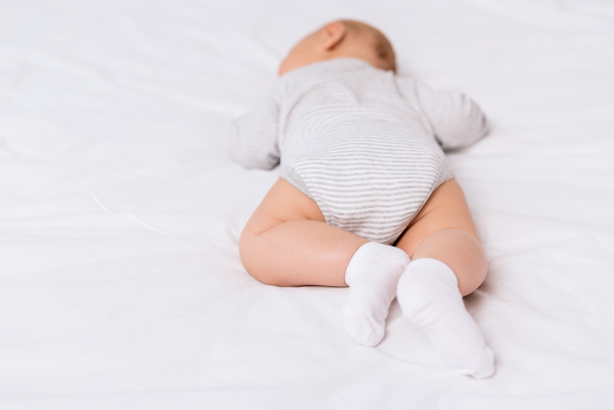 back view of infant in socks lying on bed