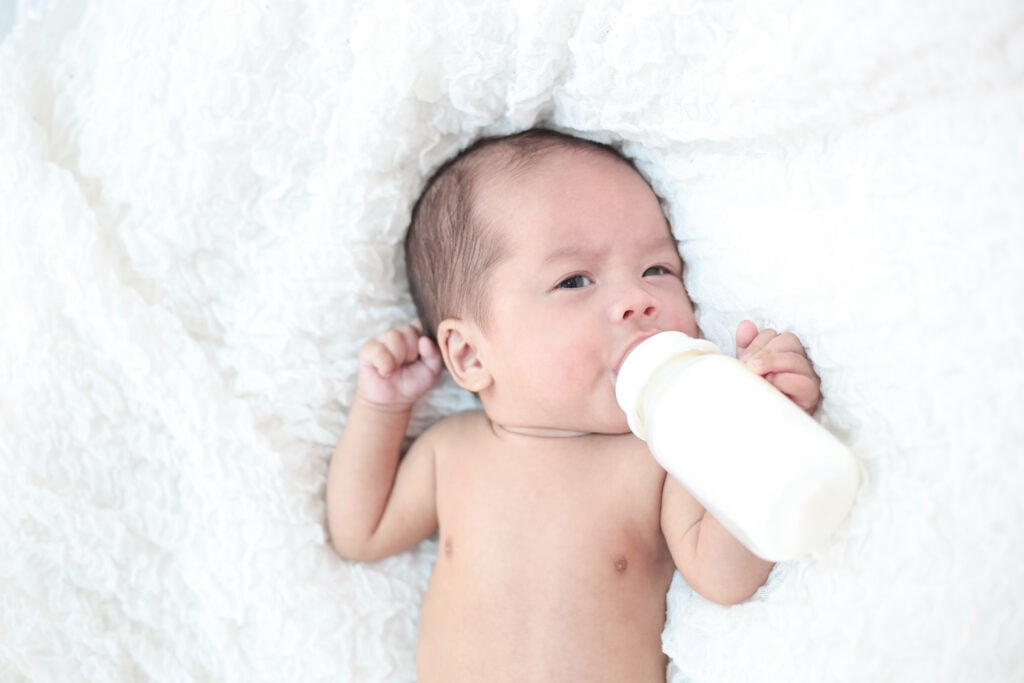 The Science Behind Bottle-Feeding Newborn babies suck milk at the bottle.